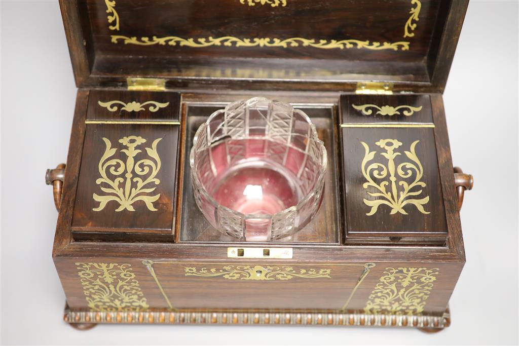 A Regency rosewood and cut brass inlaid sarcophagus shaped tea caddy, (mixing bowl restored), length 33cm